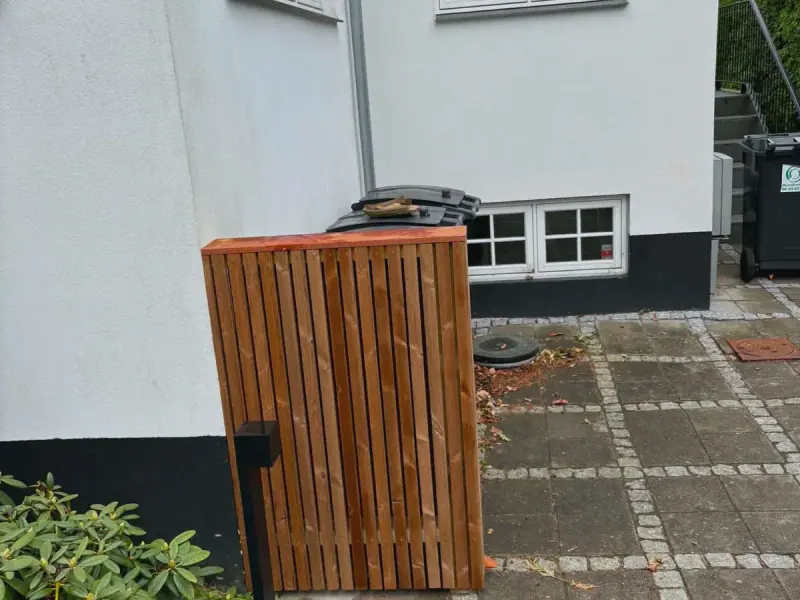 Affaldsskjuler i laseret lameltræ med massiv topplade op ad husmuren