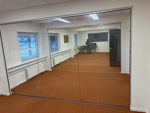 Glasparti fra gulv til loft der deler et kontorlokale
