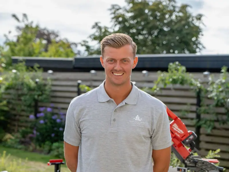 Mikkel Birch Cartey i firmapolo foran læhegnet på arbejdspladsen